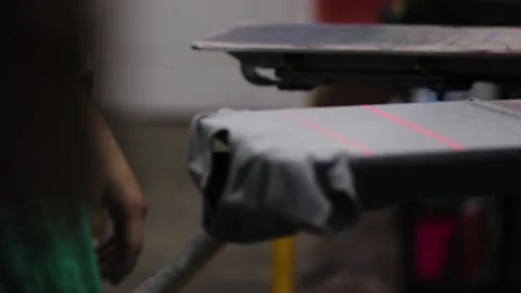 Screen printing gray shirt on automatic print press. Guy printing shirts Stock Footage 139387500