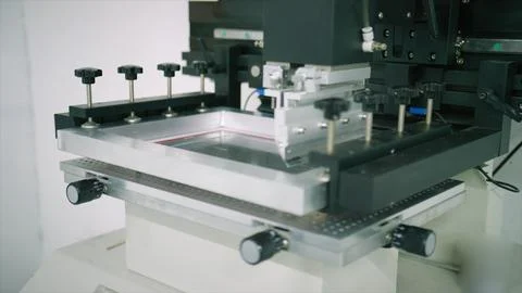 Screen printing machine applying ink to fabric in workshop Foto stock