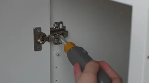 Screw driver secures cabinet door on flat pack furniture- close up Stock Footage 56071298