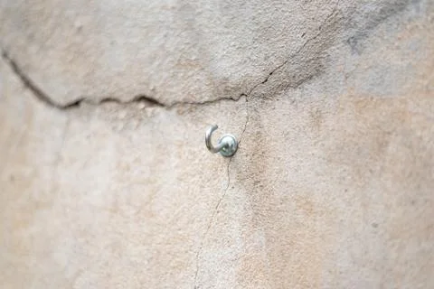 Screw with a hook shape inside a cracked concrete wall Stock Photos
