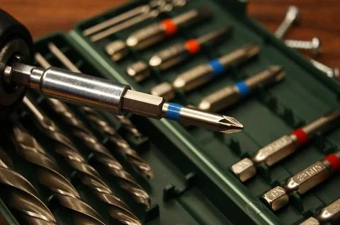 A screwdriver and a set of bits on a dark wooden table Stock Photos