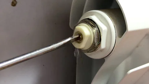 Screwdriver Bleeding Radiator Valve to Release Water in Home Heating System Stock Footage 329455859