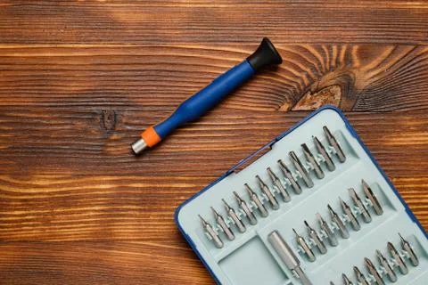 A screwdriver next to a case for interchangeable nozzles on a wooden backgrou Stock Photos