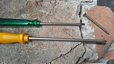 Screwdriver resting on cracked pavement during repair work. Hand tool for Stock Photos