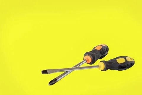 A screwdriver. A working tool. Flat and phillips screwdrivers on a yellow b.. Stock Photos