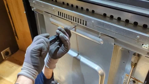 Screwing the back of a stove on Stock Footage 294260540