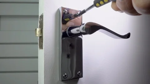 Screwing a polished chrome handle onto an interior door. Stock Footage 96372394