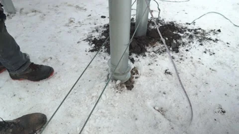 Screwing screw piles into the ground at a construction site in winter Stock Footage 148635360