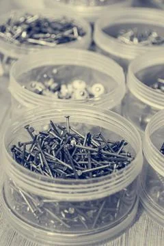 Screws and nails divided in plastic cups based on size. Stock Photos