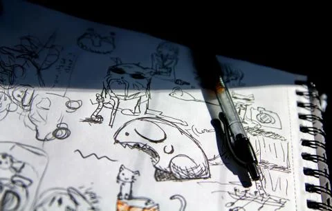 Scribbles of animated characters and other things on a drawing notebook expos Stock Photos