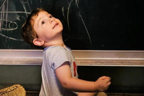 Scribbles, little boy drawing with chalk on blackboard Stock Photos