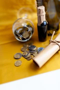 Scroll of paper with wine bootle and glass with coins on yellow background Stock Photos