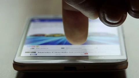Scrolling facebook posts on a smartphone with a finger Stock Footage