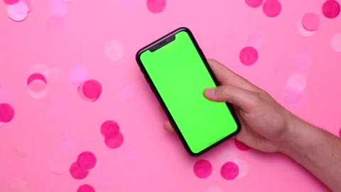 Scrolling mobile phone on pink background with confetti, male hand with phone Video stock 131760968