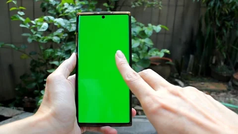 Scrolling the smartphone screen with greenscreen, with garden in the backgrou Stock Footage 291695894