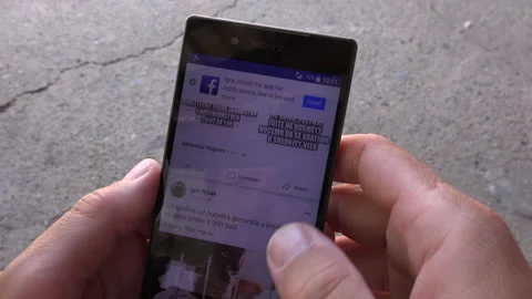 Scrolling through Facebook posts on smartphone Stock Footage 135730355