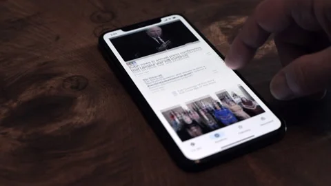 Scrolling topical news on an iphone Stock Footage 258620514