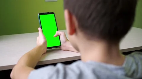 Scrolls with his finger on the touch screen. the boy is sitting with a green Stock Footage 167559463
