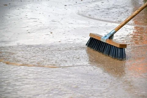 Scrubbing the floor with a brush to remove the mud after flooding Foto stock