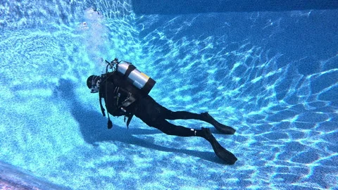 Scuba diver on bottom of pool demonstrates how breathing affects buoyancy. Stock Footage 319254241