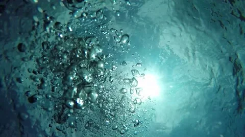 Scuba diver bubbles rising to ocean surface silhouette against sun Stock Footage
