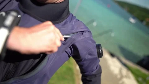 Scuba diver closing drysuit during preparation for freshwater lake dive. Cold Vídeo Stock 331342855