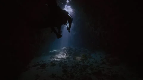 Scuba diver exiting coral cave Stock Footage 344002915
