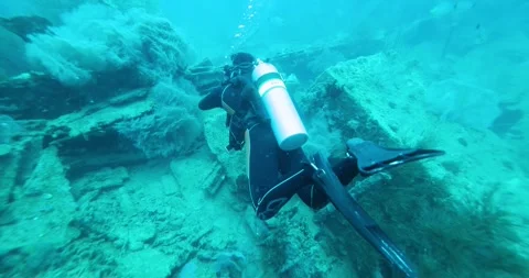 Scuba Diver Exploring Big Ship Wreck. Schools of fish swim around it Stock Footage 269139206
