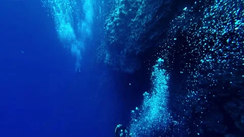 Scuba diver exploring deep blue underwater reef wall with bubbles Stock Footage 337644021