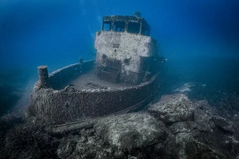Scuba diver exploring sunken shipwreck creating marine habitat Stock Photos