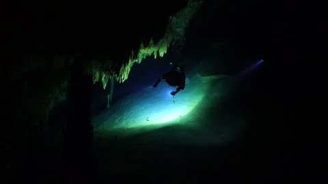 Scuba diver with a flashlight exploring a dark underwater cave with stalactites Vídeos de archivo 331341209