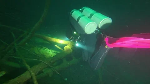 Scuba diver with a flashlight exploring a dark underwater cave system Stock-Footage 339221781