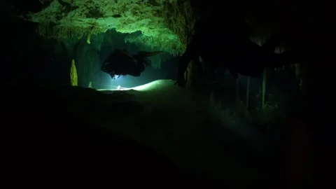 Scuba diver with a flashlight exploring a mysterious underwater cenote with 스톡 동영상 332002601