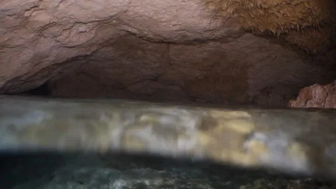 Scuba diver with a flashlight swimming inside a dark, flooded cave system with Stock Footage 332001358