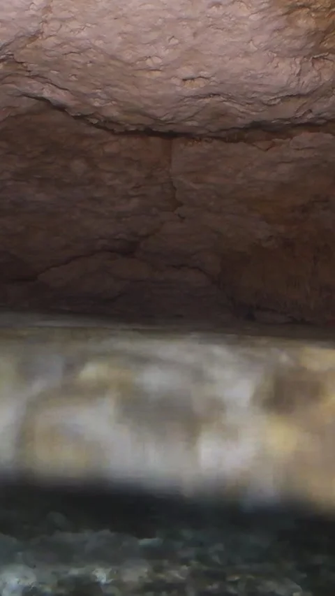Scuba diver with a flashlight swimming inside a dark, flooded cave system with Vídeos de archivo 332001377