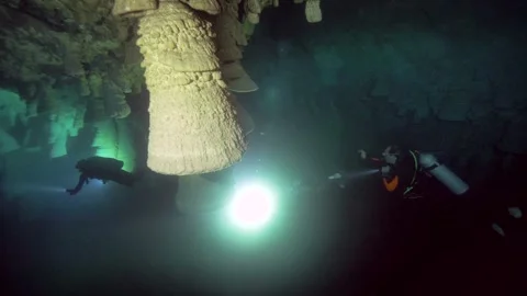 Scuba diver illuminates a giant hanging bell formation Stock Footage 341394585
