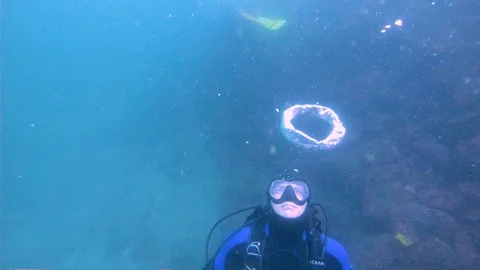 Scuba Diver Makes Bubble Ring and Keeps Diving Stock Footage 129115293