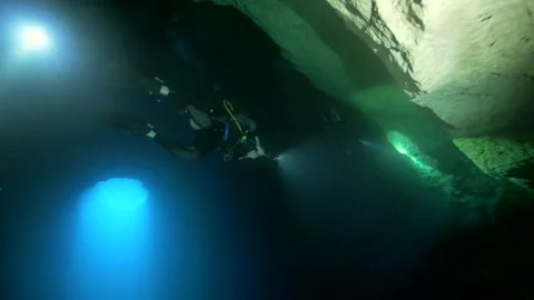 Scuba diver near limestone ceiling and blue cavern opening Stock Footage 341395041