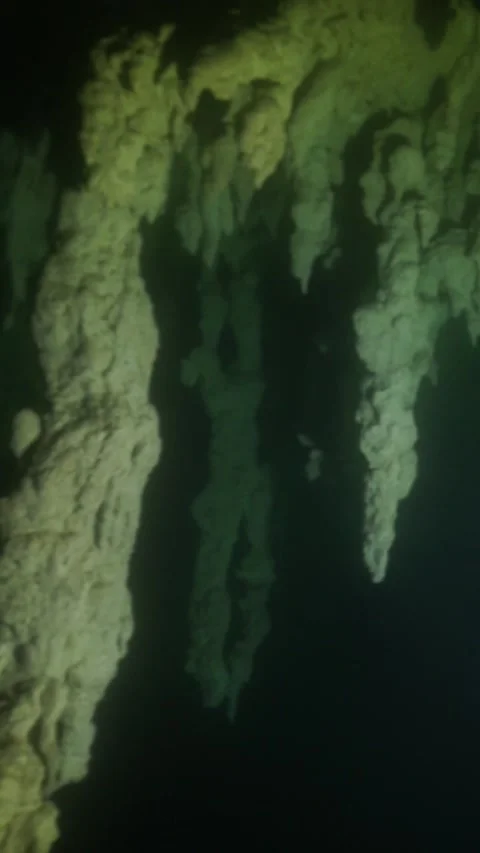 Scuba diver with a powerful flashlight illuminating stalactites in a dark, Stock Footage 332000498