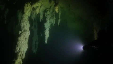 Scuba diver with a powerful flashlight illuminating stalactites in a dark, Stock-Footage 332000519