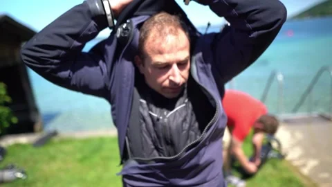 Scuba diver pulling drysuit neck seal into position while preparing for cold Stock Footage 331342969