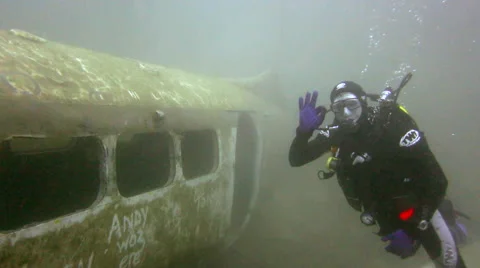 Scuba Diver swims out of plane wreck and gives the 'ok' sign Stock Footage 48587794