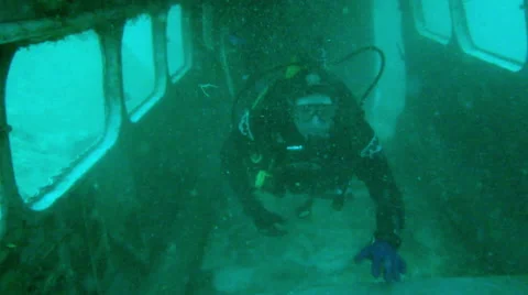 Scuba Diver swims through plane wreck up to cockpit and gives the 'ok' sign Stock Footage 48587163