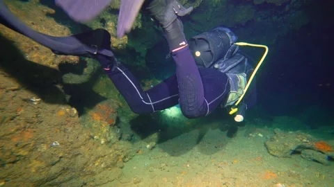 A Scuba Diver with Torch Going Inside of an Underwater Cave Stock Footage 143587865