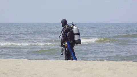 Scuba diver walking back to shore along the sea coast. Slow Motion. Stock Footage 82795633