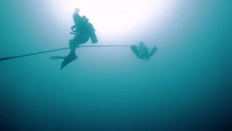 Scuba divers descending down a long rope from a boat into the ocean Stock Footage 80439600