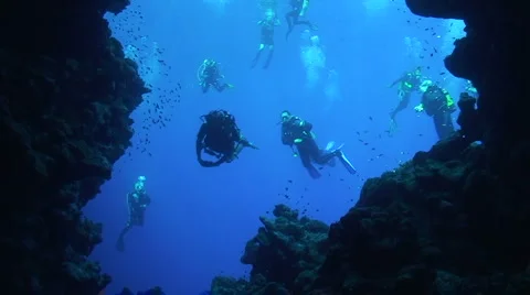 Scuba divers entering underwater cave Stock Footage