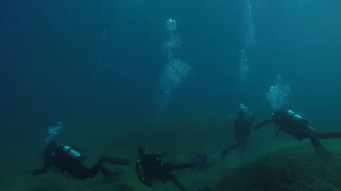SCUBA divers explore a ship wreck in blue water as seen from a GoPro Stock Footage 115008000