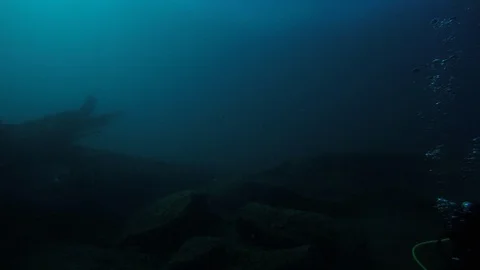 SCUBA divers explore a ship wreck in blue water as seen from a GoPro Stock Footage 115011210