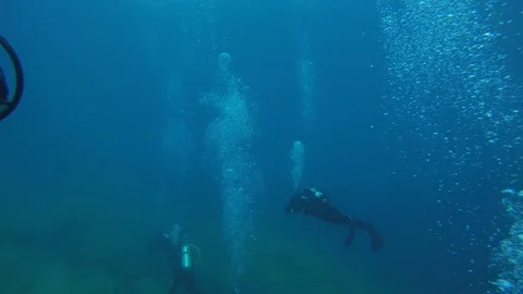 SCUBA divers explore a ship wreck in blue water as seen from a GoPro Stock Footage 115011506